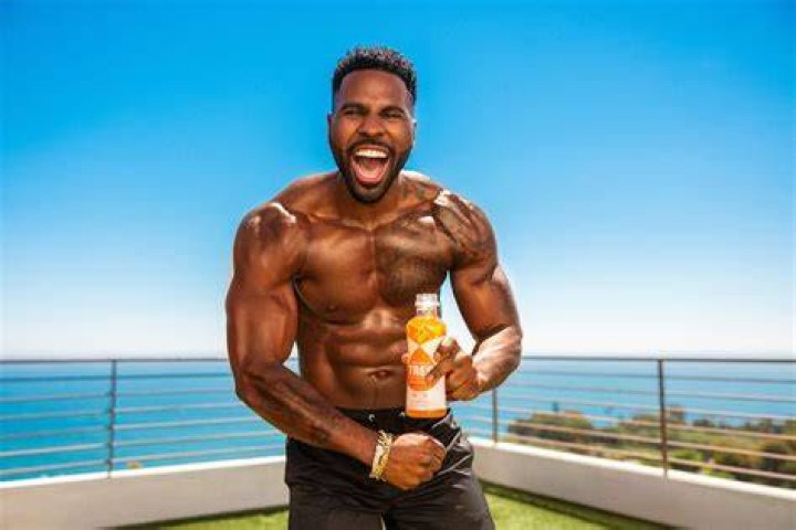 Jason Derulo’s GF Jena Frumes Sweetly Cradles Son Jason King, 4 Weeks, In Orange Mini Dress